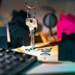 Modelos de casas en miniatura con llaves y billetes de euro, representando la rentabilidad de una vivienda de uso turístico.