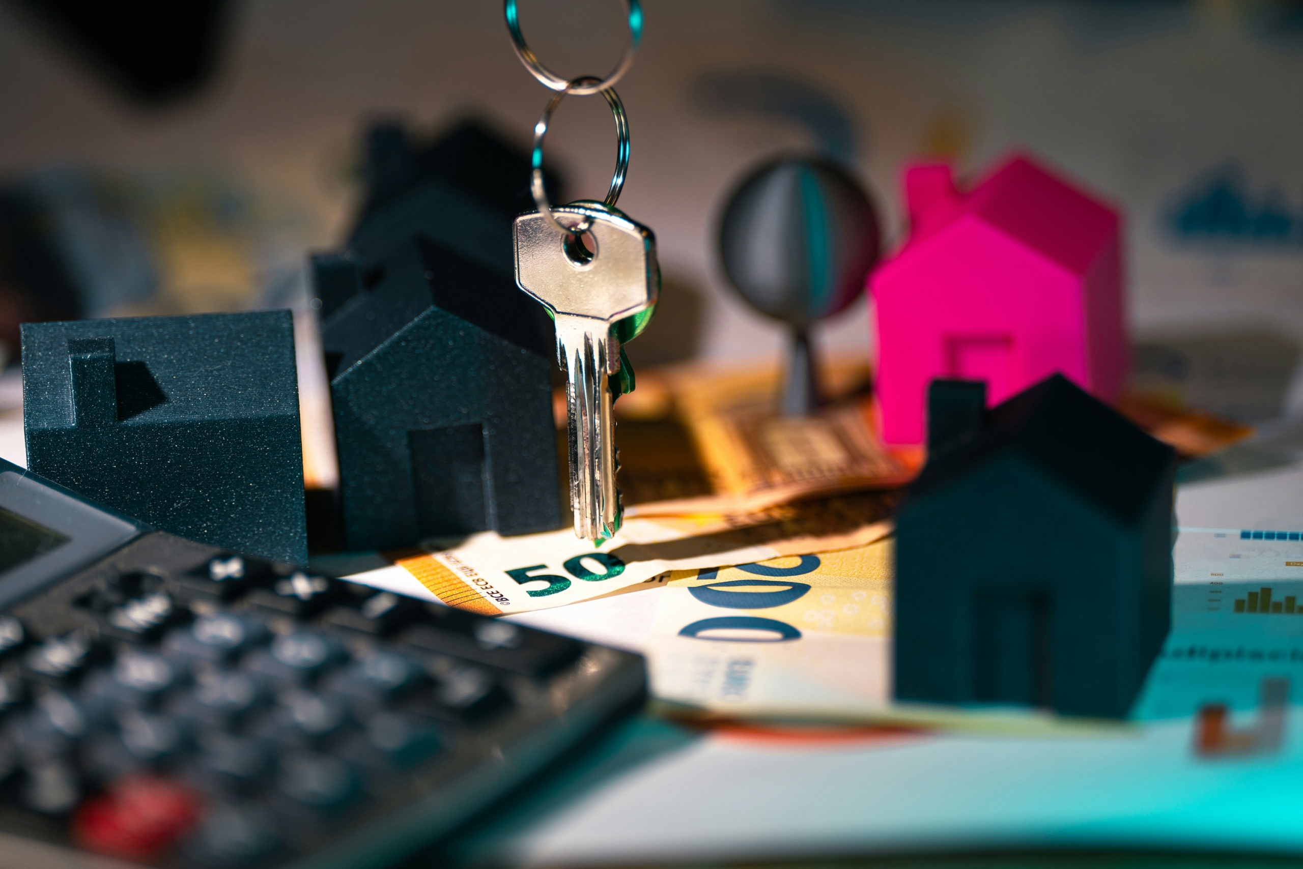 Modelos de casas en miniatura con llaves y billetes de euro, representando la rentabilidad de una vivienda de uso turístico.